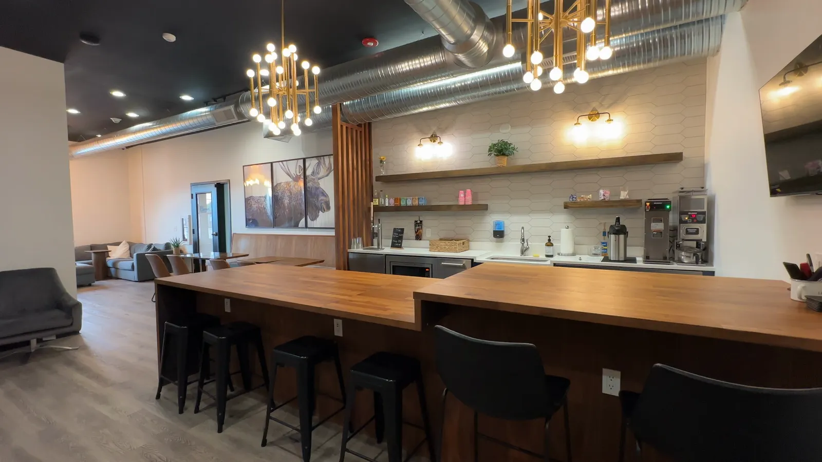 The coffee bar at The Lodge with a long walnut counter, bar seating, and pendant lights