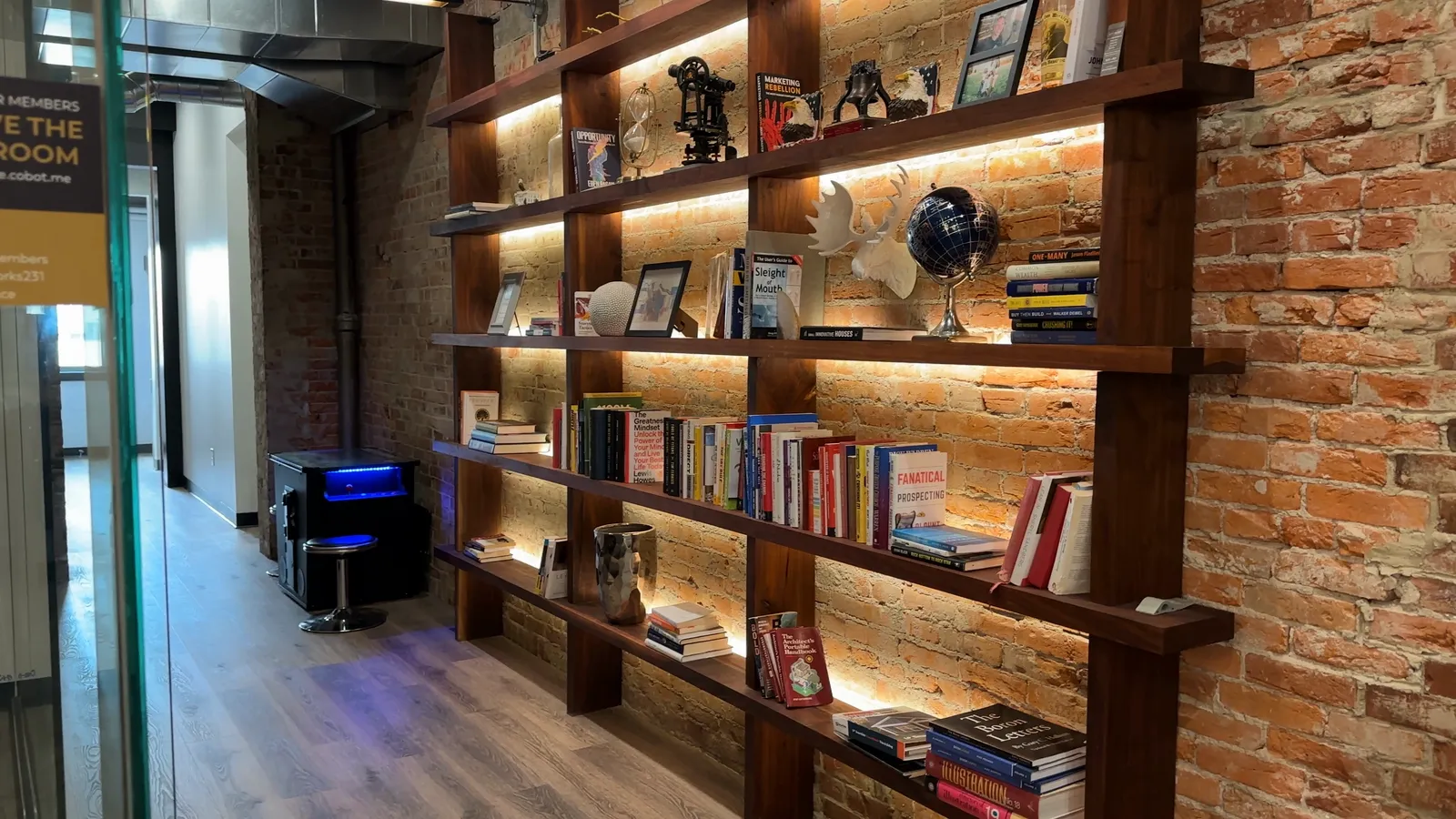 Books on warm-lit wood shelves against restored brick at The Lodge